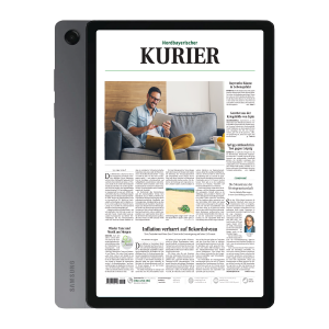 Tablet showing the front page of Nordbayerischer Kurier newspaper, with a man reading on a couch on screen